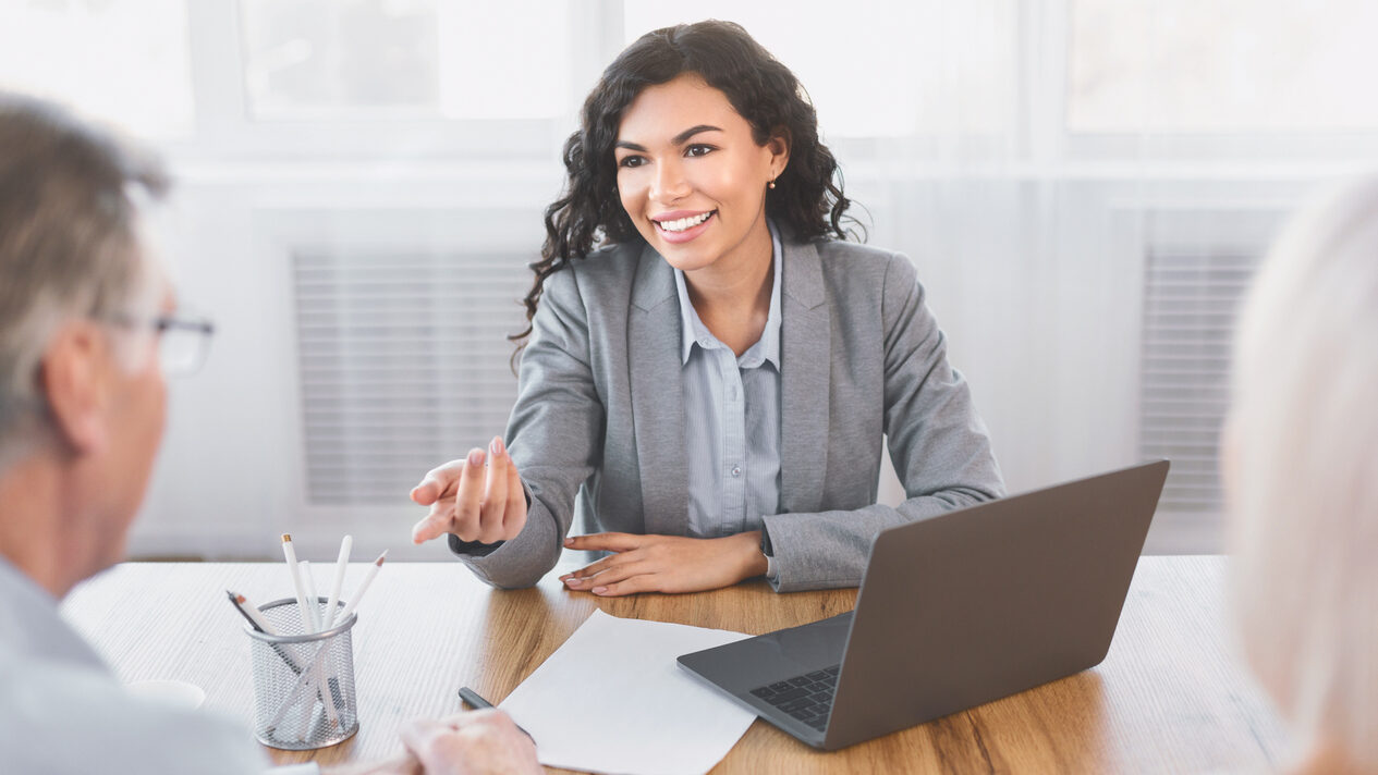 Woman smiling, sitting in her office talking to clients.