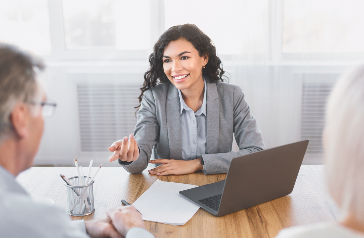 A woman real estate broker smiling and talking to a man who appears to be her client.